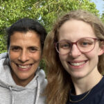 Selfie von Prof. Dr. med. Sandra Steffens und Dr. med. Marie Mikuteit, beide lächeln, im Hintergrund grüne Bäume.